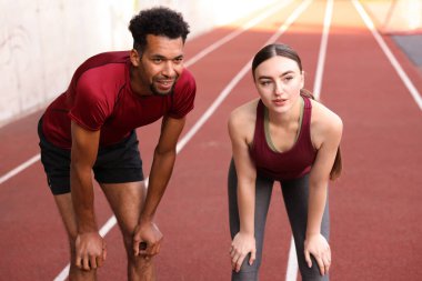Stadyumda koştuktan sonra dinlenen gülümseyen çift.