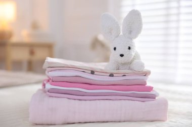 Temiz bebek kıyafetleri ve yatak örtüleri iç mekanda, yakın plan.