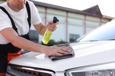 Kaputu gri mikrofiber bez ile silen adam, yakın plan.