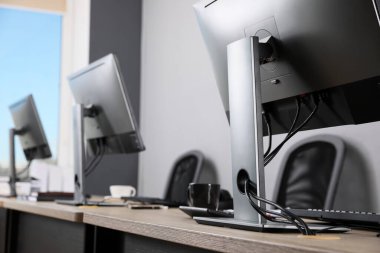 Ofisin içini aç. Açık gri duvarın yanında bilgisayarları olan modern işyerleri