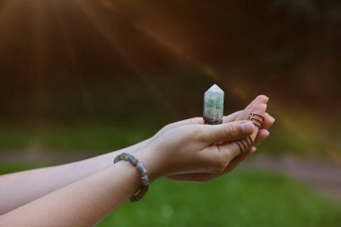 Kadın dışarıda atmosferini iyileştirmek ya da iyileştirmek için kristalle meditasyon yapıyor.