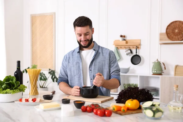 Mutfaktaki masada yemek pişiren gülümseyen adam.