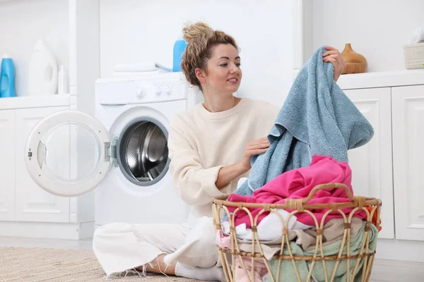 Çamaşır makinesinin yanında çamaşır makinesi olan bir kadın.