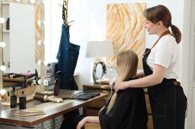 Profesyonel kuaför müşteriyle kuaförde çalışıyor.