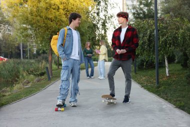 Şehir sokaklarında yürüyen bir grup genç, seçici bir odak noktası.