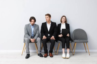 İnsanlar içeride sandalyede kuyrukta bekliyorlar.