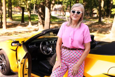 Modern Cabriolet yakınlarında güneş gözlüklü şık bir son sınıf öğrencisi.