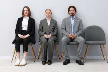 İnsanlar içeride sandalyede kuyrukta bekliyorlar.