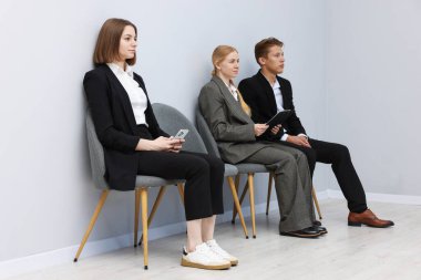 İnsanlar içeride sandalyede kuyrukta bekliyorlar.