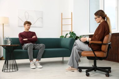 Ofiste genç bir çocukla çalışan profesyonel psikolog.