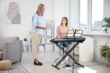 Öğretmenim kadınlara evde piyano çalmayı öğretiyor.