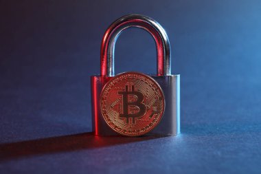 Bitcoin ve asma kilit mavi arkaplanda kırmızı ışıkta, yakın plan