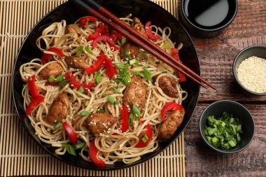 Tavuk, yeşil soğan ve sebzeli erişte ahşap masada servis edilir.