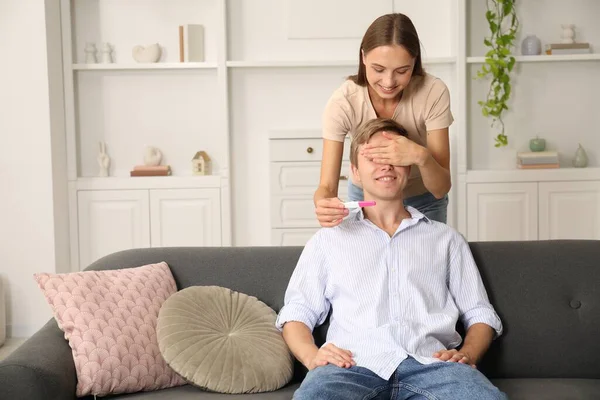 Mutlu genç bir kadın kocasına evde pozitif hamilelik testiyle sürpriz yapıyor.