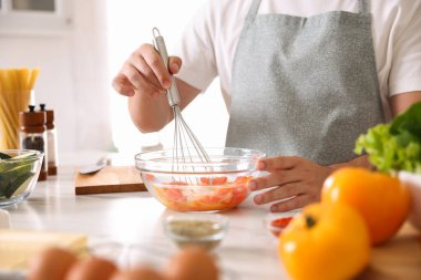 Kapalı bir masada çırpılmış yemek pişiren adam, yakın plan.