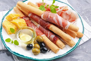 Grissini ekmekleri jambon, peynir, zeytin ve bal ile yakın plan.