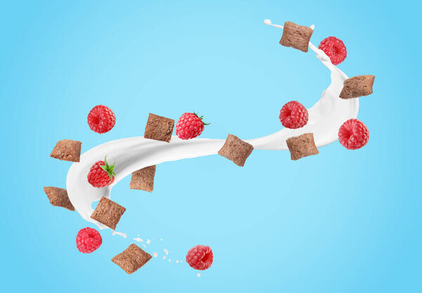 Splashing milk with sweet corn pads and fresh raspberries in air against light blue background. Healthy breakfast