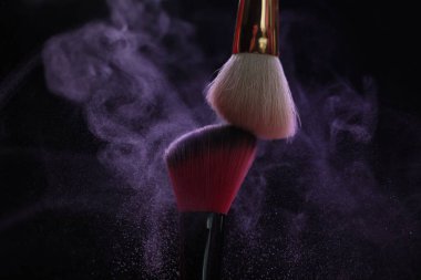 Siyah arka planda mor göz farlı makyaj fırçaları, yakın plan