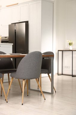 Mutfak içi yemek masası, yer ve gri sandalyelerle dolu.