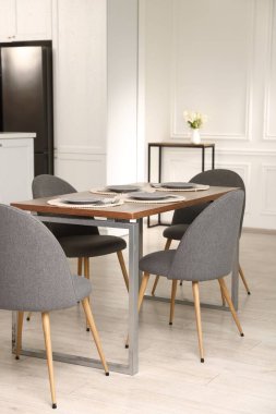 Mutfak içi yemek masası, yer ve gri sandalyelerle dolu.