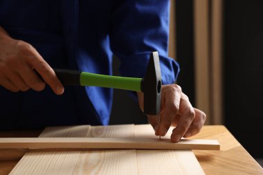 Profesyonel tamirci, kapalı alanda tahta çiviye çivi çakıyor.