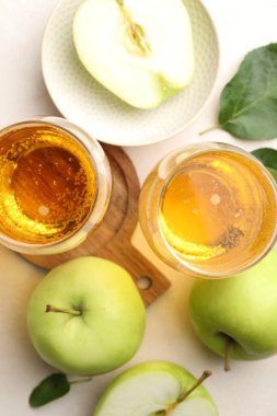 Taze elma şarabı, elmalar ve yeşil yapraklar bej masada, düz yerde.