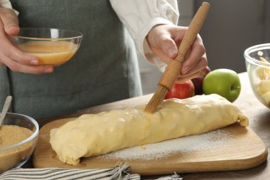 Mutfaktaki çiğ elmalı turtaya yumurta sarısı döken kadın, yakın plan.