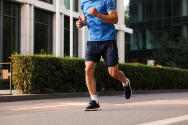 Spor giyimli bir adam caddede koşuyor, yakın plan.