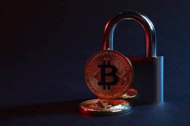 Mavi arkaplanda kırmızı ışıkta bitcoinler ve asma kilit, metin için boşluk ile yakın çekim