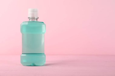 Pembe arka planda bir şişe gargara, mesaj için yer. Ağız temizliği.