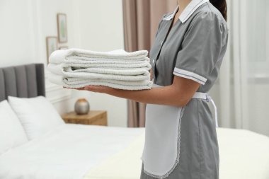 Otel odasında beyaz havlu yığını olan oda hizmetçisi, yakın plan.