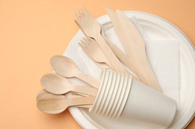 Soluk turuncu arkaplanda tek kullanımlık sofra takımı, üst görünüm