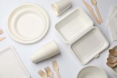 Beyaz arka planda tek kullanımlık sofra takımı ve peçeteler, düz konum