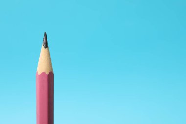 Açık mavi arka planda keskin bir grafit kalem, yakın plan. Metin için boşluk