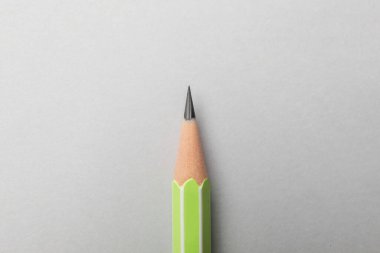 Gri arkaplanda keskin bir grafit kalem, üst görünümde.