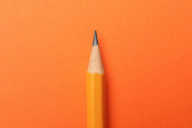 Turuncu arka planda keskin bir grafit kalem, üst görünüm.