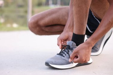 Koşucu ayakkabısının bağcığını dışarıda bağlıyor, yakın plan. Metin için boşluk