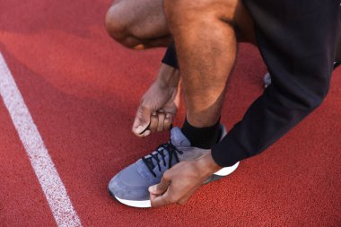 Stadyumda ayakkabısının bağcıklarını bağlayan koşucu, yakın plan.