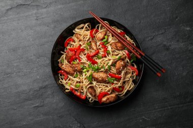 Tavuk, yeşil soğan ve sebzeli lezzetli şehriyeler siyah masada servis edilir.