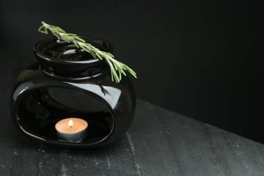 Aroma lambası, yanan mum ve siyah arka planda koyu dokulu masa üzerinde biberiye, yakın plan. Metin için boşluk