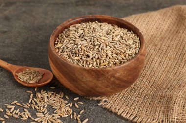 Çavdar taneleri kasede ve kaşık gri masada, yakın plan.