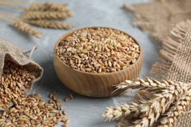 Açık gri masada buğday taneleri ve çiviler, yakın plan.