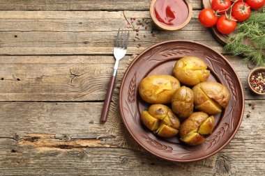 Lezzetli fırında patates, çatal, baharat ve ürünler ahşap masada, düz yerde. Metin için boşluk