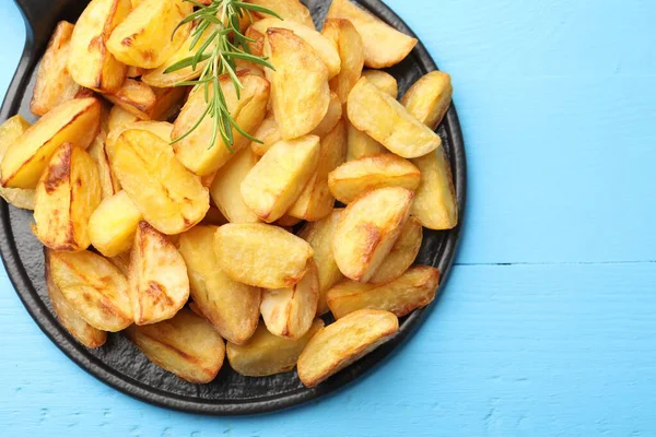Açık mavi ahşap masada biberiyeli lezzetli fırında patates, üst manzara. Metin için boşluk