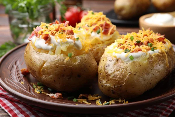 Ekşi kremalı fırında patates, yeşil soğan, peynir ve pastırma, yakın plan.