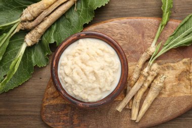 Lezzetli yaban turpu sosu ve ahşap masa üzerinde kökler.
