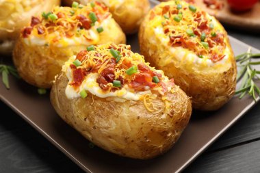 Siyah ahşap masada lezzetli fırınlanmış patatesler, yakın plan.