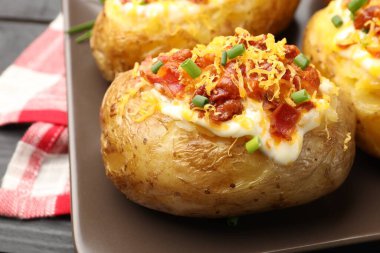 Lezzetli fırında patatesler siyah masada, yakın plan.