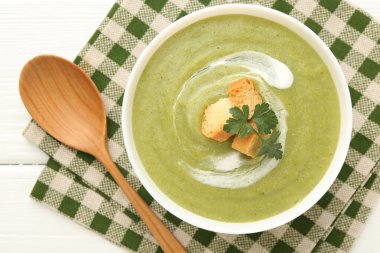 Tasty broccoli cream soup with croutons in bowl on white wooden table, top view