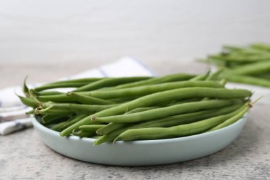 Fresh green bean pods on grey textured table, closeup